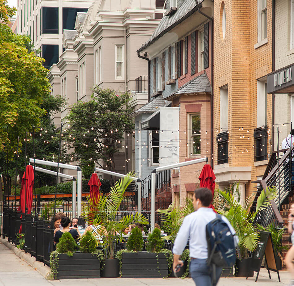 A male pedestrian walks past a restaurant outdoor patio area