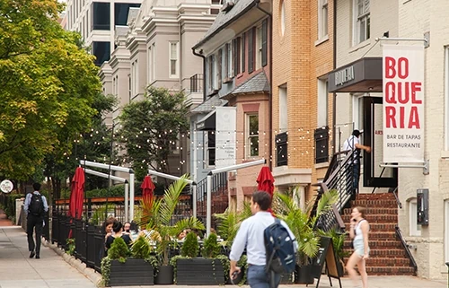 A male pedestrian walks past a restaurant's outdoor patio area