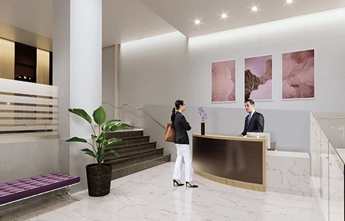 Woman talks to a male receptionist in waiting area by elevators