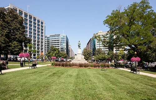 A tall statue stands in the middle of public green space